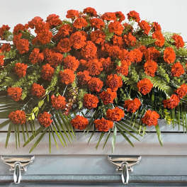 Orange carnation casket spray with palm fronds