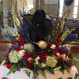 Cowboy hat and boots surrounded by red, white, and blue flowers