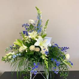 White lilies and blue flowers arranged in a white vase
