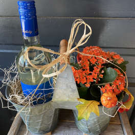 Gift basket with a wine bottle and orange potted flowers