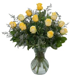 Yellow roses arranged in a clear glass vase with airy filler