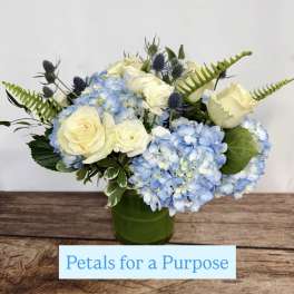Blue hydrangeas and white roses arranged in a green vase