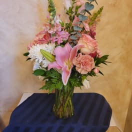 Pink lily and mixed pastel flowers in a glass vase