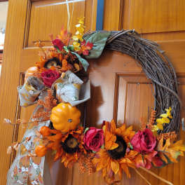 Fall wreath with sunflowers, roses, and pumpkins on a wooden door