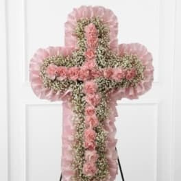 Pink floral cross on an easel with ruffled trim