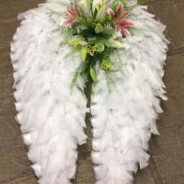 White feathered funeral spray with lilies and pink accents