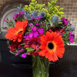 Bright mixed bouquet with orange gerbera daisies in a glass vase