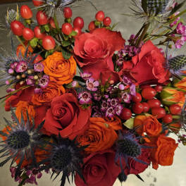 Bouquet of red and orange roses with purple thistle-like flowers