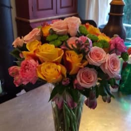 Mixed bouquet of pink and yellow roses in a clear glass vase
