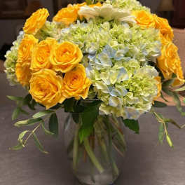 Yellow roses and pale hydrangeas in a glass vase