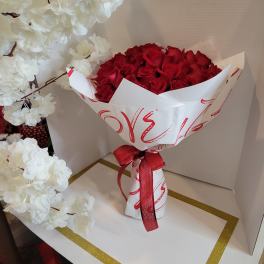Bouquet of red roses wrapped in white paper with a red ribbon