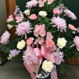 Pink and white floral arrangement with roses, carnations, and lilies in a vase