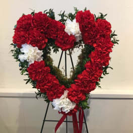 Heart-shaped wreath of red and white carnations on an easel