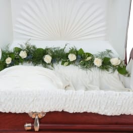 White roses arranged on a white-lined casket