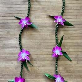 Braided floral garland with purple orchid blossoms on a wood background
