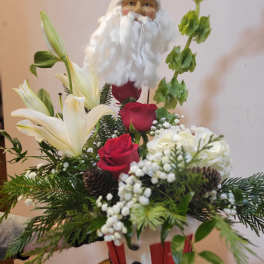 Santa figurine holding a floral arrangement with red roses and white lilies