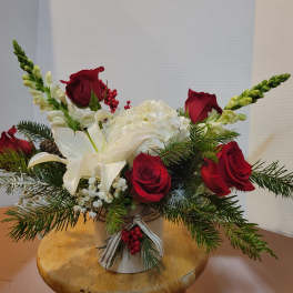 Red roses and white lilies in a small vase with evergreen accents