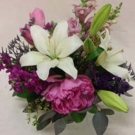 Bouquet of white lilies, pink peonies, and purple flowers in a vase