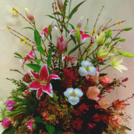Mixed flower arrangement in a wicker basket with lilies and roses