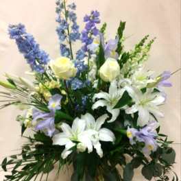 Tall bouquet of white lilies, pale roses, and blue-purple flowers