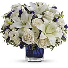White lilies and roses arranged in a blue glass vase