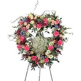 Heart-shaped floral wreath on an easel with a central urn