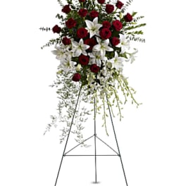 Standing floral spray of red roses and white lilies on an easel