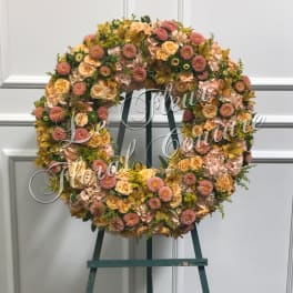Large floral wreath on an easel with pink, peach, and yellow blooms