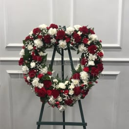 Heart-shaped wreath of red and white carnations on an easel