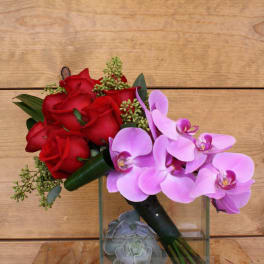 Red roses and pink orchids in a glass cube vase with succulents