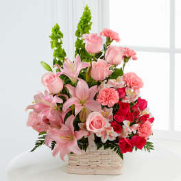 Pink roses, lilies, and carnations in a basket arrangement