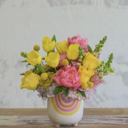 Yellow tulips and pink flowers in a white ceramic vase
