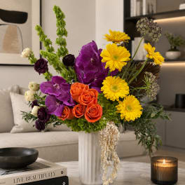 Bright mixed bouquet in a silver vase with purple, orange, and yellow flowers