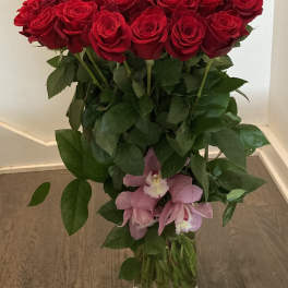 Tall bouquet of red roses with pink orchids in a glass vase