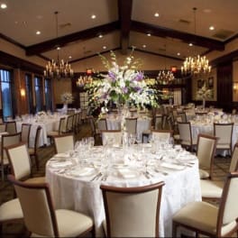Round banquet tables with tall floral centerpieces in a formal dining room