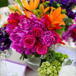 Bright mixed bouquet with pink roses, orange lilies, and purple flowers in a vase