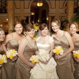 Bride and bridesmaids holding white and yellow bouquets indoors