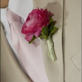 Pink boutonniere pinned to a beige suit jacket