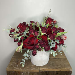 Red and burgundy roses arranged in a white vase.