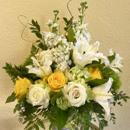 Yellow and white floral arrangement in a silver vase
