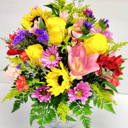 Colorful mixed bouquet with sunflowers, roses, lilies, and daisies in a white vase