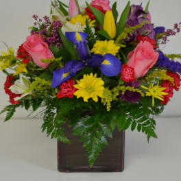 Colorful mixed flower arrangement in a square glass vase