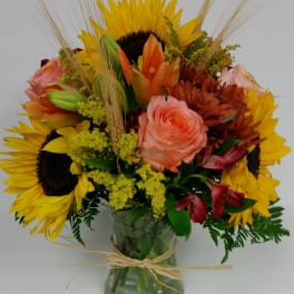 Bouquet of sunflowers, roses, and lilies in a glass vase