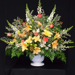 Large floral arrangement in a white urn with lilies and roses