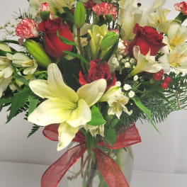 Bouquet of red roses and white lilies in a glass vase with a red ribbon
