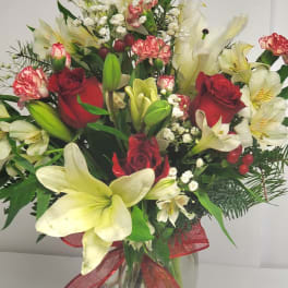 Bouquet of red roses and white lilies in a glass vase with a red ribbon