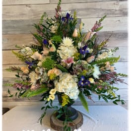 Large mixed floral arrangement in a black pedestal vase
