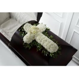 White floral cross arrangement on a dark casket