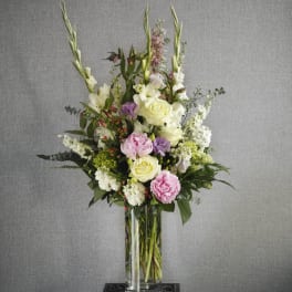 Tall floral arrangement in a clear glass vase with pink, white, and lavender blooms
