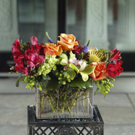 Colorful bouquet of orange roses and red flowers in a glass vase